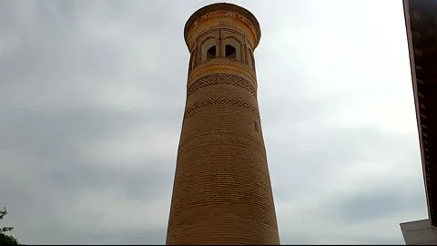 Daytime tilt-up shot of an ancient brick minaret tower in Bukhara Stock Footage 335954122