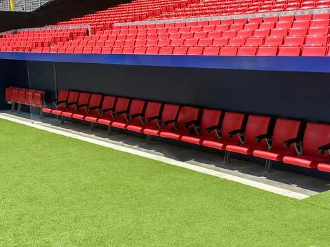 Daytime View of Red Stadium Seating and Green Artificial Turf Field Stock Photos