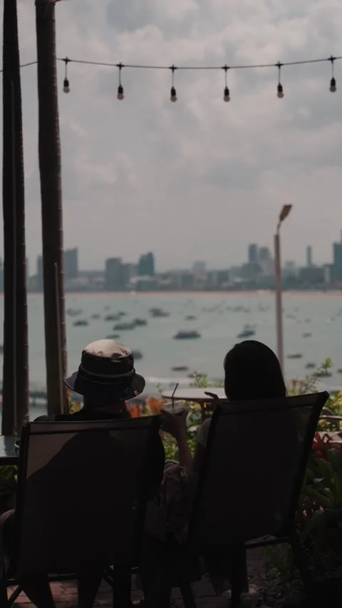 Daytime visitors relaxing at a beachfront cafe while enjoying Pattaya Bay Stock Footage 338246264