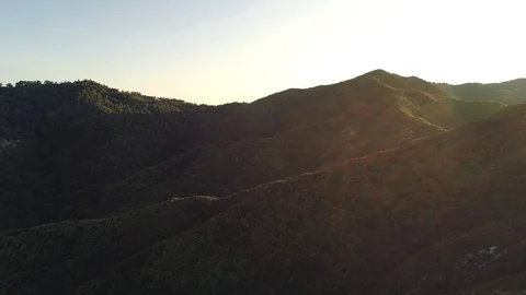 Dazzling aerial sunset flying over forested hills with lens flare. Shot pans Video stock 87517341