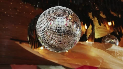 A dazzling disco ball radiates light in a vibrant setting, ideal for Stock Footage 324676903