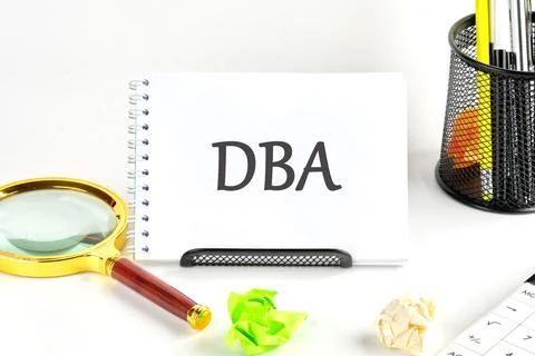 DBA short for Data Base Administrator. DBA written on a blank sheet of a desk Stock Photos