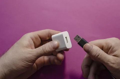 DC adapter and USB data cable in male hands. Stock Photos