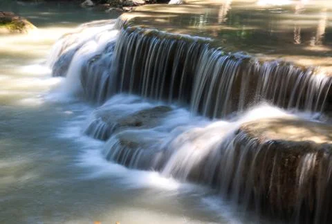 De focused small waterfall in the forest blurred background Stock Photos