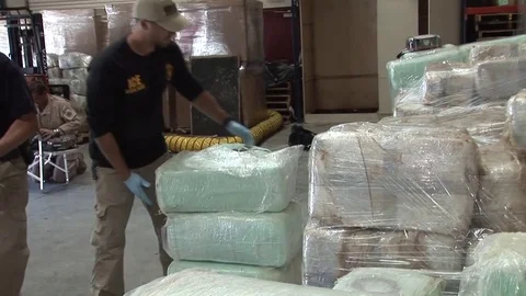 DEA agents stack confiscated drugs in a warehouse. Stock Footage 74807172