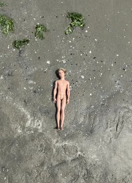 Dead doll on the beach Stock Photos