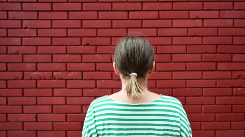 Dead end concept, rear view of casual brunette female facing the red brick wa Video stock 253589849