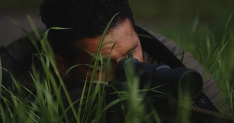 Deadly precision - stealthy sniper aiming its target while hiding in grass. Stock Footage 277181542