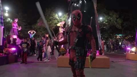 Deadpool cosplay guy with costume, sword and gold desert eagle pistol gesturing Stock Footage 320850864