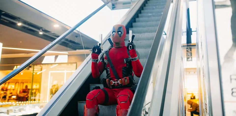 Deadpool cosplayer posing with guns on escalator staircase Stock Photos