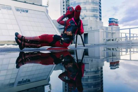 Deadpool cosplayer posing sitting with weapon Stock Photos