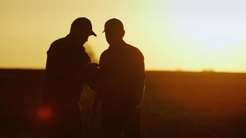 Deal in agribusiness. Two male farmer communicate on the field, use a tablet - Stock Footage