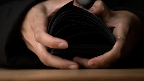 A Dealer Flips Through a Deck of Black Cards on a Table Stock-Footage 270400493