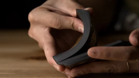 A Dealer Shuffling Flips Through a Deck of Black Cards on a Table Stock Footage 270398798