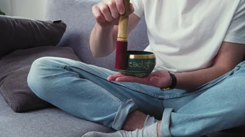 Dealing with depression and stress. Young man using tibetan singing bell bowl at Stock Footage 153615443