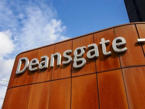Deansgate sign on a rust-colored wall against a vibrant blue sky. Mancheste.. Stock Photos