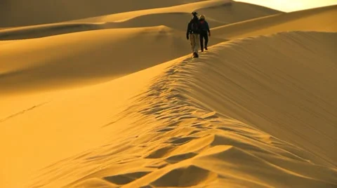 Death Valley Hikers Walk Across Huge Sand Dune Mountain in Desert Sun Stock Footage
