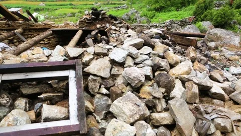 Debris of demolished house surrounded by greenery and prayer flags on the side Stock Footage 77446097