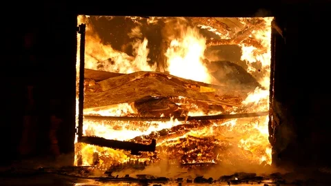 Debris on fire seen through garage door at a warehouse involved in flames Stock Footage 123198910