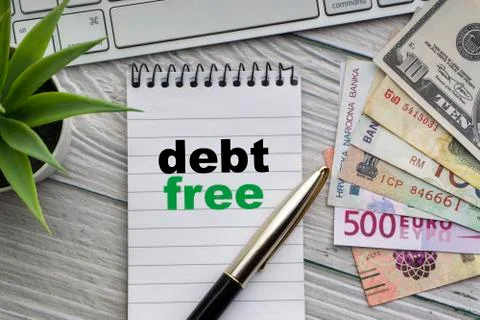 DEBT FREE text with notepad, keyboard, decorative vase, fountain pen and bank 库存照片