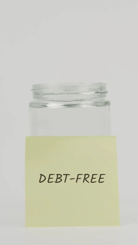 Debt-free text or word on yellow sticky note attached to glass jar with hand Stock Footage 311710748