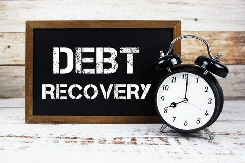 Debt Recovery text message and alarm clock on wooden background Foto stock