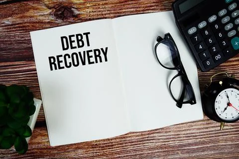 Debt Recovery text on note page with alarm clock and calculator top view on.. Stockfoto's