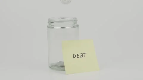 Debt text or word on yellow notes on empty jar hand inserting coin Stock Footage 307070360