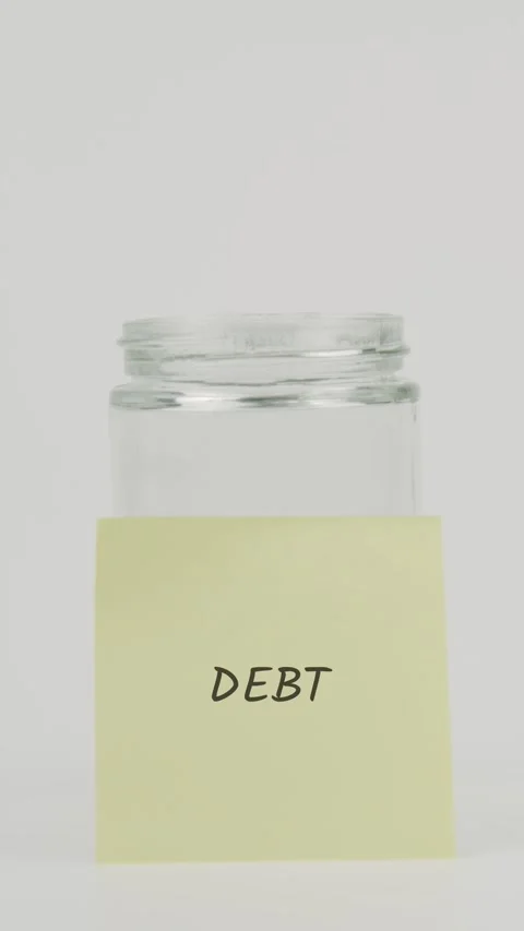 Debt text or word on yellow sticky note attached to glass jar with hand Stock Footage 311710091
