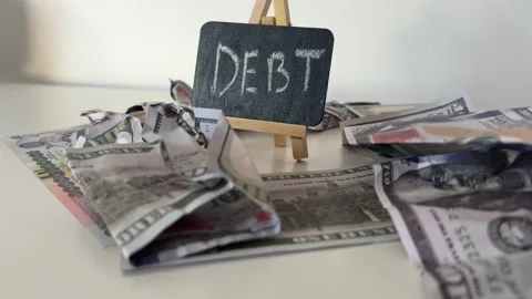 Debt Written On Blackboard With US Dollar Bills And Cash For Financial Trouble Stock Footage 339064136