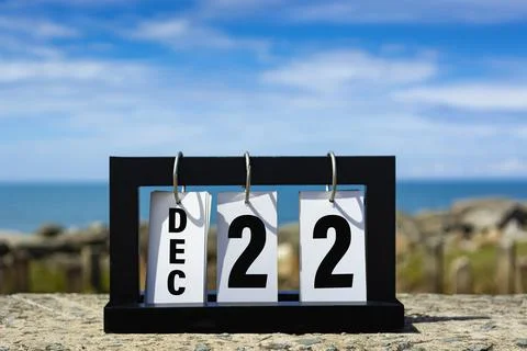 Dec 22 calendar date text on wooden frame with blurred background of ocean. Stock Photos