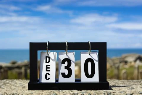 Dec 30 calendar date text on wooden frame with blurred background of ocean. Stock Photos