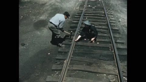 Decade: migrant workers build railroad track by hand. Man holds nail in sleeper. Video stock 189936606