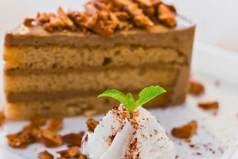 Decadent slice of layered coffee cake with whipped cream and nuts Stock Photos