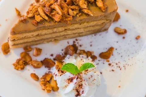 Decadent slice of layered coffee cake topped with nuts and cream Stock Photos