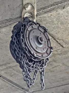 Decayed Mechanical Fixture. Weathered Mechanical Part Suspended From Concre.. 库存照片