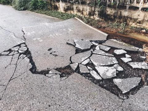 Decayed road paved asphalt distressed road surface with damaged, peeling dama 스톡 사진