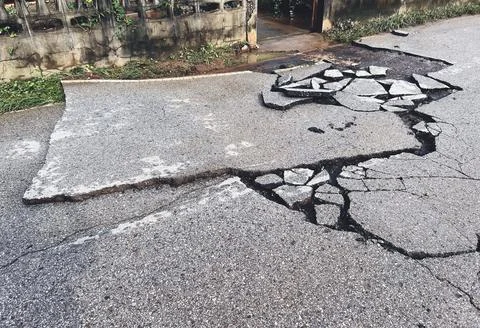 Decayed road paved asphalt distressed road surface with damaged, peeling dama Stock Photos