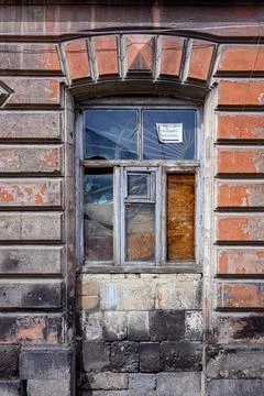 Decaying brick building window with broken glass and peeling paint Stock Photos