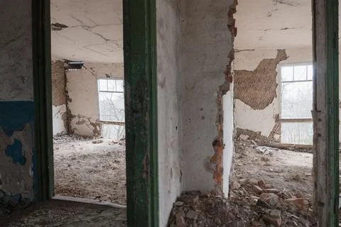 Decaying empty room with shattered plaster, exposed brickwork, rubble-strewn  库存照片