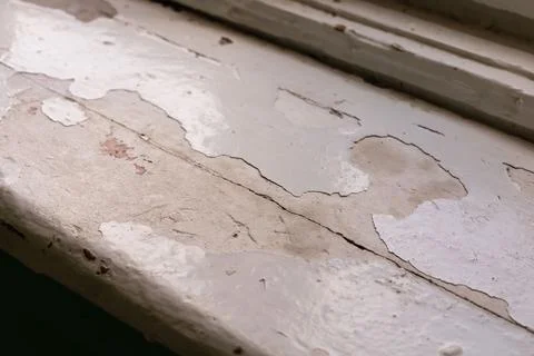 The decaying window sill of an aged structure displays layers of flaking pain Stock Photos