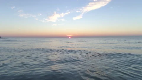 Decelerating Aerial Shot of the Sun Setting on the Ocean Horizon Stock Footage 136482516