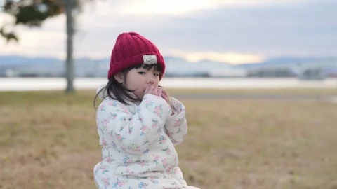 In December 2024, a 3-year-old girl eats a matcha-flavored cookie at a park near 스톡 동영상 297031317