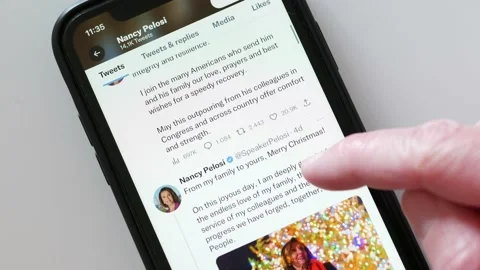 DECEMBER 29, 2022: Scrolling Nancy Pelosi Twitter Profile Page on an iPhone Stock Footage 228849299