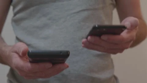 Deciding between compact and large smartphone holding two devices Stock Footage 337997906