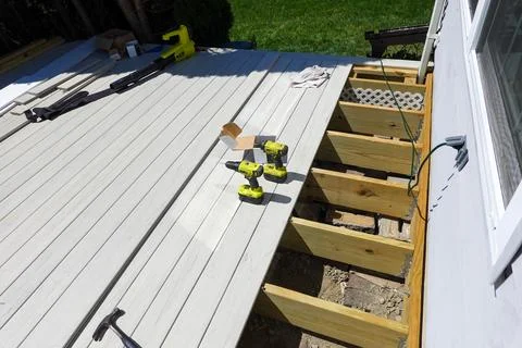 Deck boards partially installed over wooden joists on new deck foundation w.. Stock Photos
