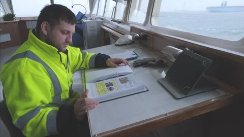 Deck cadet sits and studies navigational documentation Stock Footage 133037560