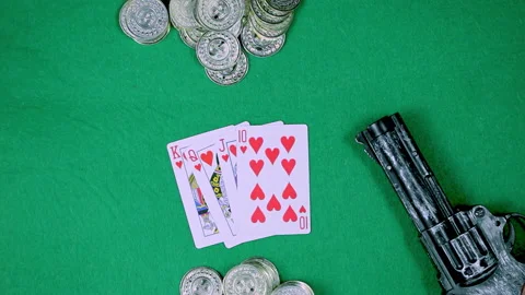 A deck of cards, coins and a gun are on a green table Video stock 237487564