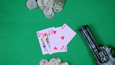 A deck of cards, coins and a gun are on a green table Video stock 237487572