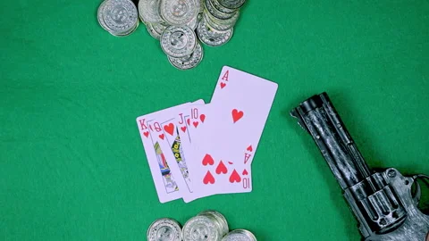 A deck of cards, coins and a gun are on a green table Video stock 237487589